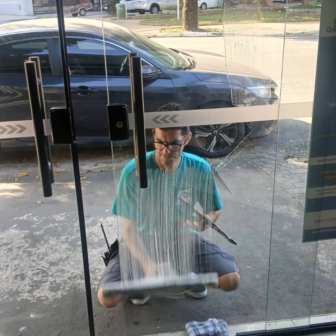 Profissional da ARM limpando a porta de vidro de um estabelecimento comercial
